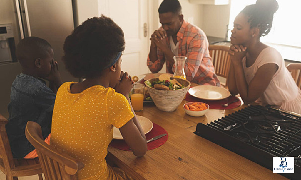 Family gathered around the dining table, praying together before a meal.